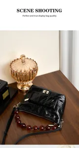 Détail d'un sac en cuir ciré noir avec poignée en perles ambre et fermoir vintage en métal