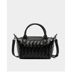 Detail shot of black woven leather handbag showing intricate texture and metal zipper