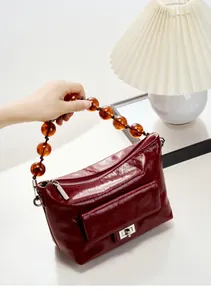 Détail de la texture cuir ciré bordeaux avec anse en perles d'ambre et fermoir argenté