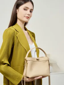 Minimalist beige leather bucket bag with gold clasp and adjustable strap for women