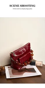 Détail du sac en cuir bordeaux avec chaîne en perles ambre et texture brillante