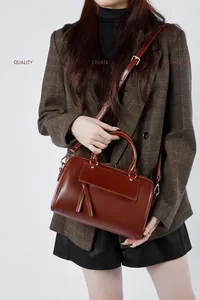 Close-up of brown leather Boston bag with double tassels and vintage bronze hardware