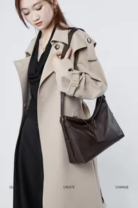 Detail view of dark coffee leather texture and metal buckle on women tote shoulder bag