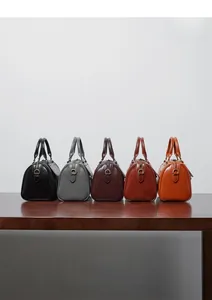 Detailed display of Boston handbags in five colors on a wooden table with soft lighting