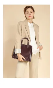 Vertical leather tote bag in dark wine red carried by model in professional suit