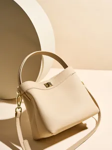 Elegant beige pebbled leather bucket bag with top handle and gold twist lock closure
