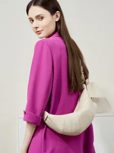 Minimalist beige leather croissant bag with quilted pleated texture worn on shoulder