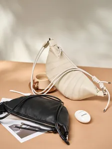 Minimalist leather croissant bag with pleated details and knotted strap in black and cream