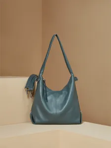 Detail of grey-blue leather tote bag with pebble grain texture and adjustable strap