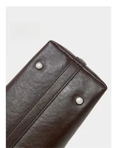 Detail of dark brown leather bag base with protective silver studs and dual stitching