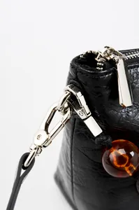 Détail du cuir ciré vintage avec quincaillerie argentée et perle d'ambre décorative