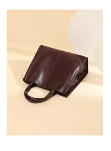 Detail of minimalist dark brown leather tote bag with vertical stitching and smooth finish