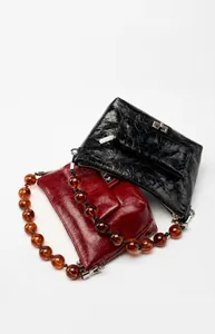 Détails macro des textures en cuir plissé brillant et chaînes en perles ambrées de sacs