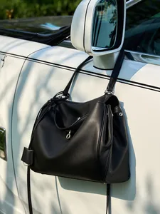 Grande borsa tote in pelle nera con fibbia argentata appesa allo specchietto di un'auto di lusso