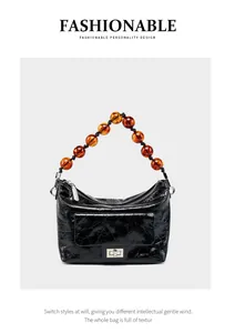 Détail du sac à main plissé en cuir huilé noir avec poignée en perles ambrées et fermoir