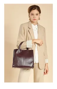 Detail of the high-quality deep burgundy leather tote bag with sturdy handles and metal feet
