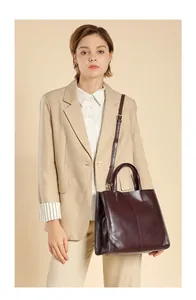 Detailed view of burgundy leather tote bag styled with a beige blazer for office commute