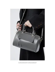 Close-up of dark grey leather boston bag with golden studs and knotted tassel detail