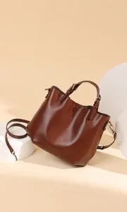 Vista dettagliata di una borsa tote in pelle marrone con doppi manici e tracolla regolabile