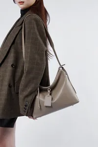 Model showing a dark khaki leather hobo shoulder bag with a wide strap and minimalist design