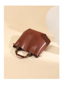 Dettaglio della borsa tote in pelle marrone con texture liscia e fibbie metalliche