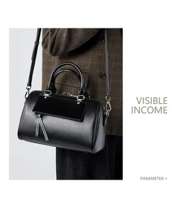 Model wearing a black leather Boston bag with tassels and gold hardware accents