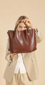 Borsa tote in pelle marrone tenuta da modella con blazer beige dal look professionale