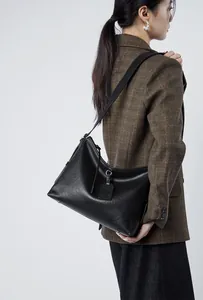 Detailed side view of black genuine leather hobo bag with wide strap on a model