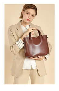 Dettaglio della borsa tote in pelle marrone scuro portata da una modella in abito da ufficio