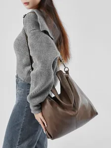 Brown leather tote bag with lychee texture and slouchy design shown on shoulder