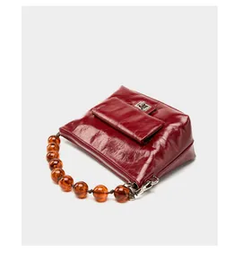 Détail du sac en cuir ciré rouge avec texture plissée et poignée en perles d'ambre