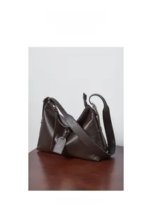 Detailed view of brown leather tote bag texture and adjustable strap on wood surface
