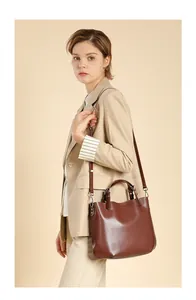 Dettaglio della borsa tote in pelle marrone indossata da una modella in tailleur beige