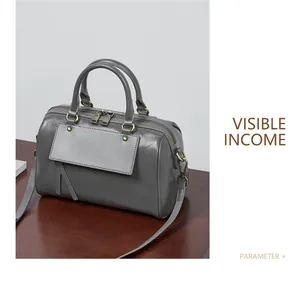 Detail view of a gray leather Boston handbag featuring dual handles and metallic zipper