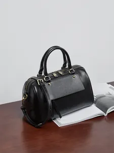 Detail shot of black leather Boston bag with gold hardware and front magnetic flap pocket