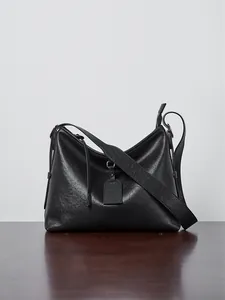 Detail view of the black leather tote bag with silver hardware and a leather hangtag