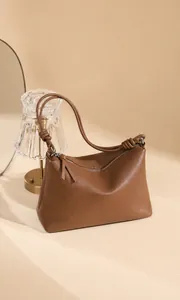 Nahaufnahme der braunen Ledertasche mit geflochtenen Knotendetails und Quasten-Reißverschluss