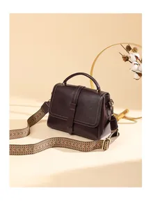 Detail of vintage brown leather handbag featuring a textured strap and elegant gold hardware