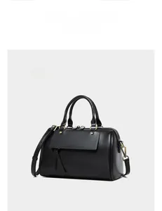 Detail view of black leather boston bag with brass hardware and adjustable shoulder strap