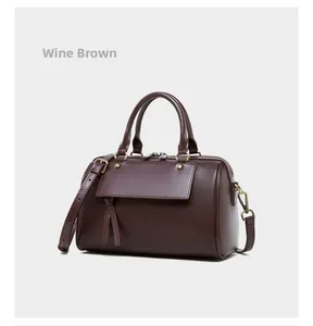 Close-up of wine brown genuine leather Boston bag with vintage tassels and metal hardware