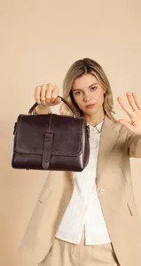 Detailed view of deep wine red leather handbag with white stitching and top handle
