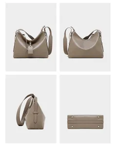 Detail view of taupe leather tote bag showing wide strap, side buckles and metal feet