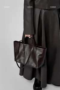 Dettaglio della borsa tote in pelle marrone scuro con texture liscia e logo in metallo