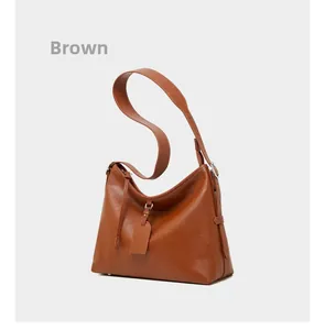 Detail shot of brown leather tote bag with wide strap and metallic adjustable buckle