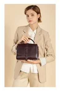 Detail of red-brown leather handbag styled with beige blazer for elegant business look