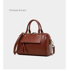 Close-up of vintage brown leather Boston bag with retro gold metal hardware and strap