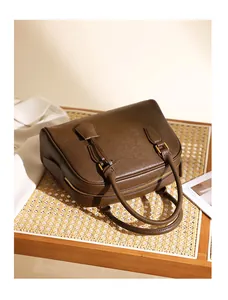 Dettaglio di borsa Boston in pelle marrone scuro con cerniere dorate su rattan