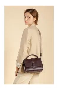 Side view of dark brown leather handbag with handle and woven strap on a model