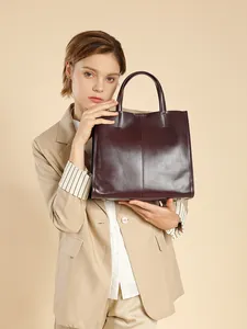 Deep burgundy leather tote bag with vertical stitching shown in a minimalist fashion setting
