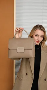 Detail of taupe pebbled leather handbag featuring single handle and silver hardware